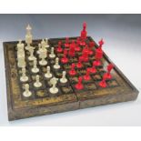 A 19th century red and white bone chess set together with a lacquer board, the dark squares of the