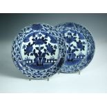 A pair of early 18th century Arita blue and white plates, each painted centrally with a vase of
