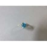 A blue zircon and diamond ring, the slightly oval cut vivid blue zircon claw set to tapered