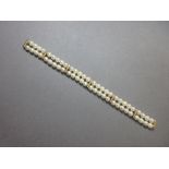A cultured pearl and diamond bracelet, the twin rows of uniform 6.5-7mm pearls held by five bar