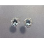A pair of aquamarine and diamond cluster earstuds, each with an oval cut aquamarine millegrain
