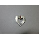 A ruby set heart shaped brooch by Tiffany & Co, the pierced white metal heart with ridged finish set