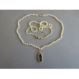 A cultured pearl necklace with gloved hand clasp and another with an amethyst pendant, the first
