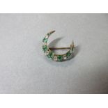 An emerald and diamond crescent brooch, the closed crescent with seven graduated emerald cut