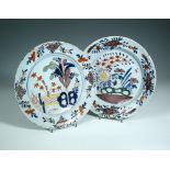 Two 18th century Delft polychrome plates, the centres painted with colourful garden scenes with