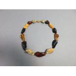 A mixed amber nugget necklace, the fifteen graduated polished lump beads of various ambers of