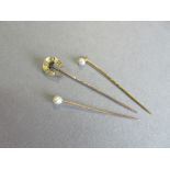 A diamond set horseshoe stick pin together with two pearl stick pins, the horseshoe set at intervals