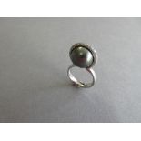 A platinum, diamond and cultured Tahitian pearl ring by Paul Spurgeon, designed as an open figure-