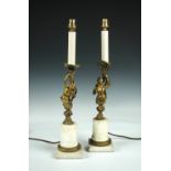 A pair of late 19th century gilt bronze and white marble candlesticks, now as lamps, cast as the