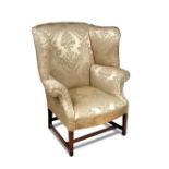 A George III mahogany framed wing armchair, upholstered in a green and gold damask fabric, on