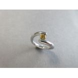 A platinum and fancy orange-yellow diamond crossover ring, the round brilliant cut diamond of