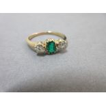 An emerald and diamond three stone ring, the emerald cut emerald of vivid rich green and good