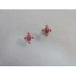 A pair of cabochon ruby earstuds, each earring of pierced diaper outline enclosing a collet set oval