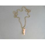 An oriental carved pink coral pendant mounted in gold and on an associated gold chain, the pendant