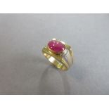 A star ruby single stone ring, the oval cabochon ruby set horizontally in a collet on a flat