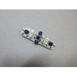 An Art Deco sapphire and diamond brooch set to the centre with a line of three oval cut sapphires