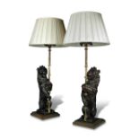 A pair of 19th century carved oak heraldic lions supporting gothic brass lamp holders, the rampant
