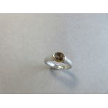 A fancy colour modern cut single stone diamond and platinum ring, the pale brown hued round