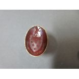 A large carved cornelian signet ring, the oval intaglio carved with an armorial composed of a shield