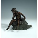 Demange, a patinated bronze of a young boy, sitting contemplatively upon a rock beside a basket of