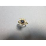 A diamond and sapphire quatrefoil ring, at the centre a round cabochon sapphire and radiating from
