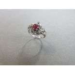 A ruby and diamond foliate knot ring, the central round cut ruby claw set in a pierced design of