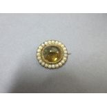 A heliodor and seed pearl brooch, the oval deep cabochon heliodor (yellow beryl) in a closed back