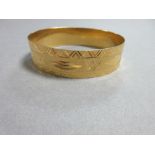 A bright cut bangle that tests for high carat gold, the 1.7cm wide bangle engraved all round the