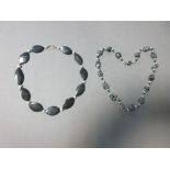 Two black hardstone and cultured pearl necklaces, the first of flat navette-shaped polished banded