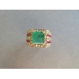 A large emerald, diamond and ruby ring, the 9 x 8mm emerald cut emerald four claw set in a border of