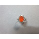 A fire opal and diamond cluster ring, the oval cabochon deep orange fire opal claw set between
