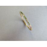 A diamond and emerald set hinged bangle, the uniform 3.2mm wide bangle channel set to the front with