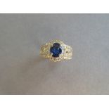 A sapphire and diamond cluster ring, the oval cut sapphire in a scallop edged border of round