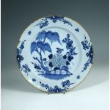 An 18th century Delft blue and white plate, decorated with a fenced garden with willow trees, the
