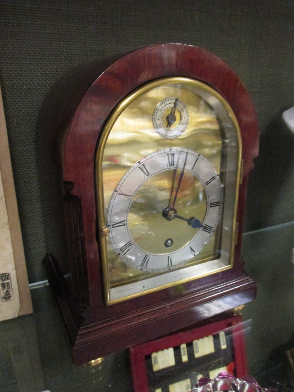 A figured mahogany domed top mantle timepiece with brass dial signed Pearce & Sons, Leicester, circa