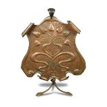An Arts and Crafts copper fire screen, the repoussé shield embossed with stylised foliate motifs