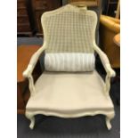 A carved and white painted French style salon chair with caned seat and back