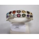 A multi-gemset hinged bangle, the broad tapering bangle half set with two rows of mixed faceted