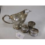 A silver sauceboat and three napkin rings