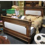 A late 19th century French walnut double bedstead with carved cresting, base and mattress, the