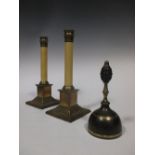 A pair of brass footed white columnar candlesticks and a handbell