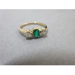 An emerald and diamond three stone ring, the emerald cut emerald of vivid rich green and good