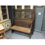 A Gothic oak settle with stained glass panel back