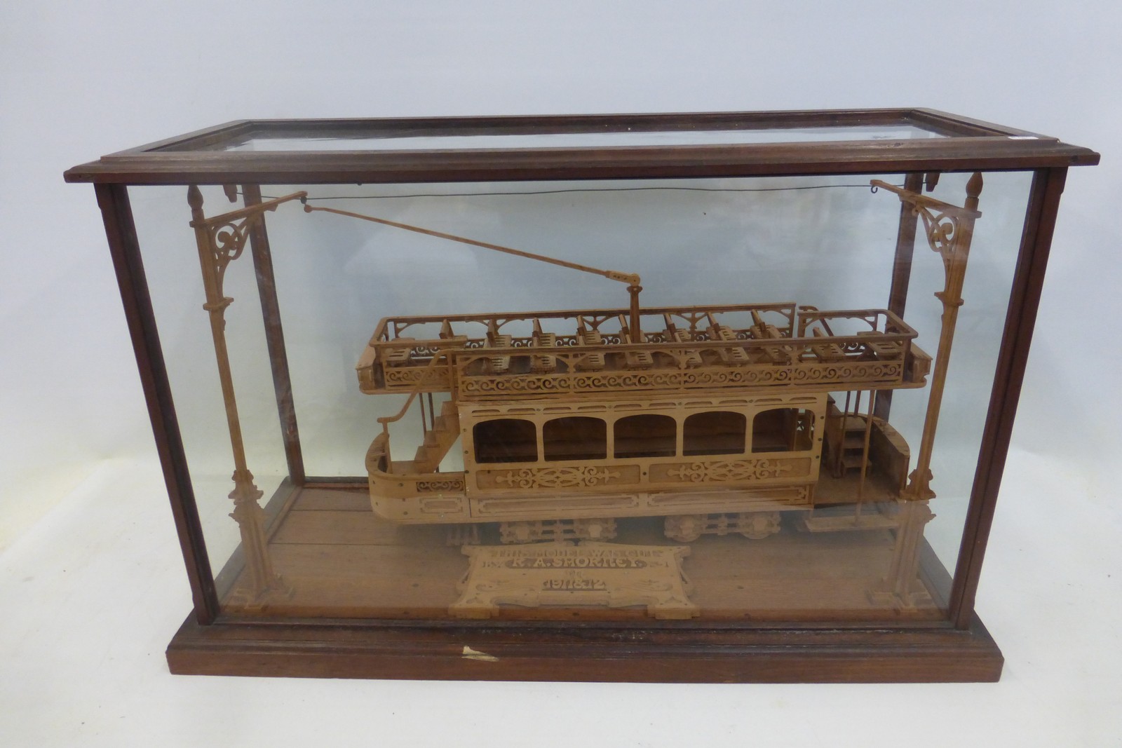 A glass display cabinet with an electric American Tram with plaque inscribed "This model was cut