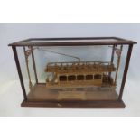 A glass display cabinet with an electric American Tram with plaque inscribed "This model was cut