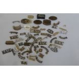 A box of assorted regimental WWI and WWII shoulder title brasses, including the Red Cross 42