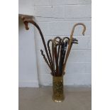A brass stick stand with an assortment of walking sticks including horn.