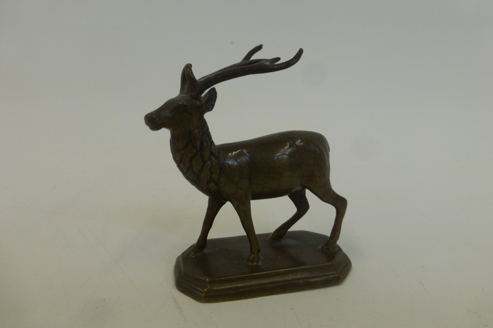 A bronzed figure of a standing stag.