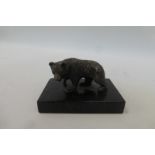 A cast metal figure of a bear cub mounted on a marble base.