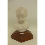 A parionware bust of a child mounted on a mahogany base.